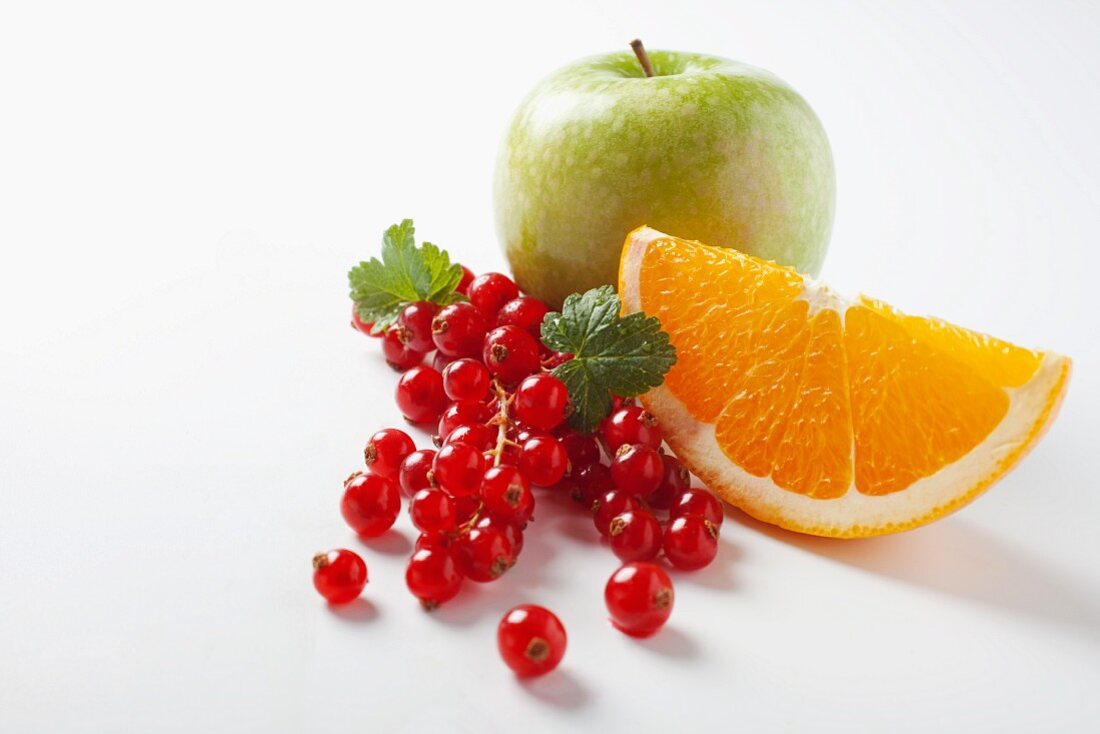 Redcurrants, an orange wedge and an apple