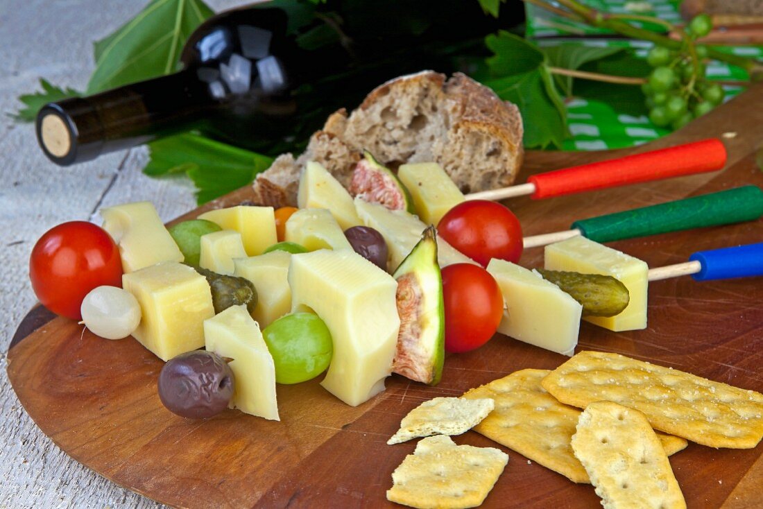 Cheese, fruit and vegetables on sticks with crackers, bread and red wine