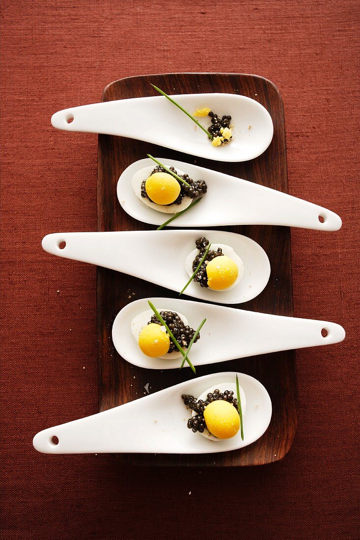 Spoon canapes with quail's eggs and caviar