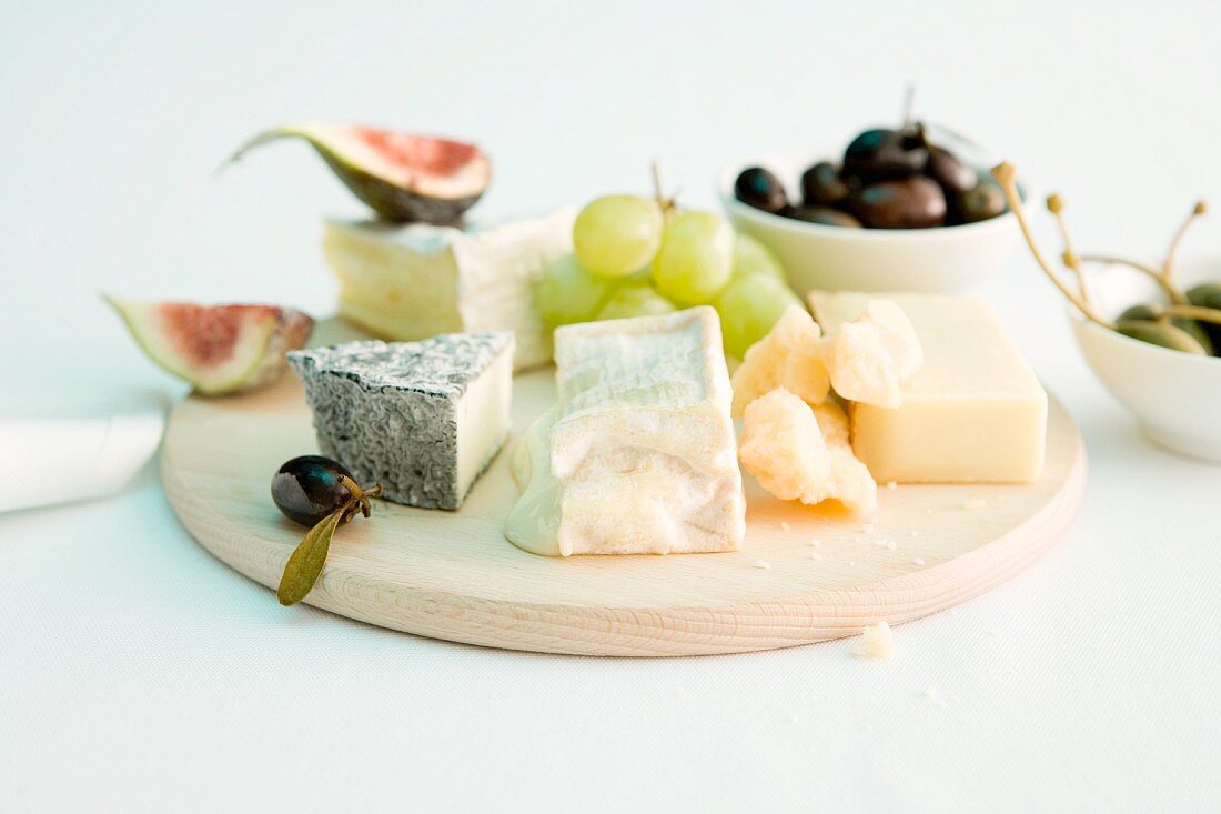 A cheese platter with grapes, figs and olives