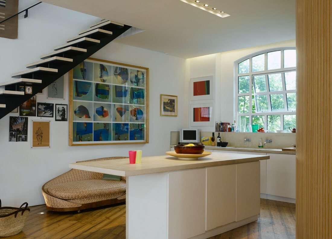 Open-plan kitchen with central island, sofa & floating staircase