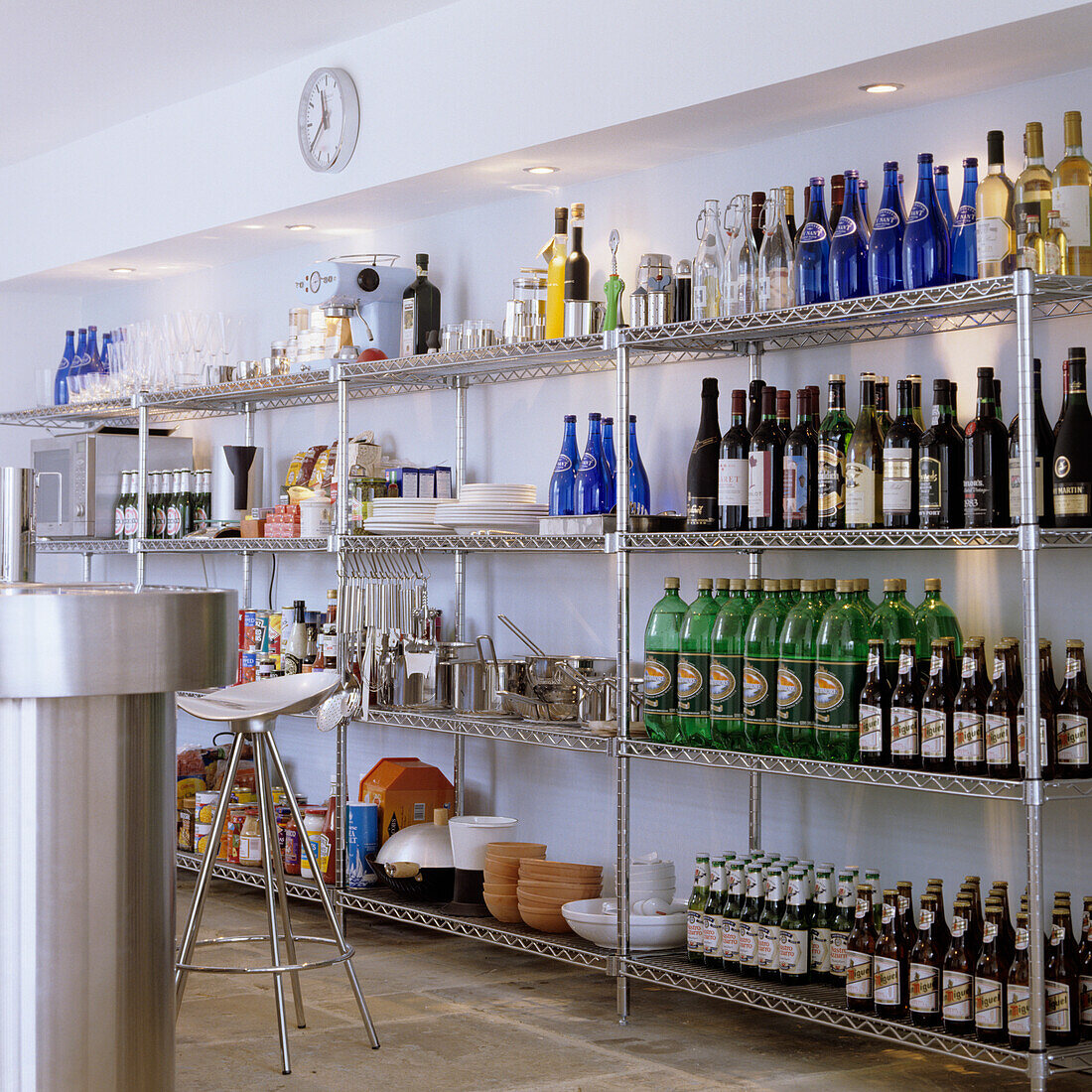 Kitchen with metal shelves filled with bottles, glasses, bowls and kitchen utensils