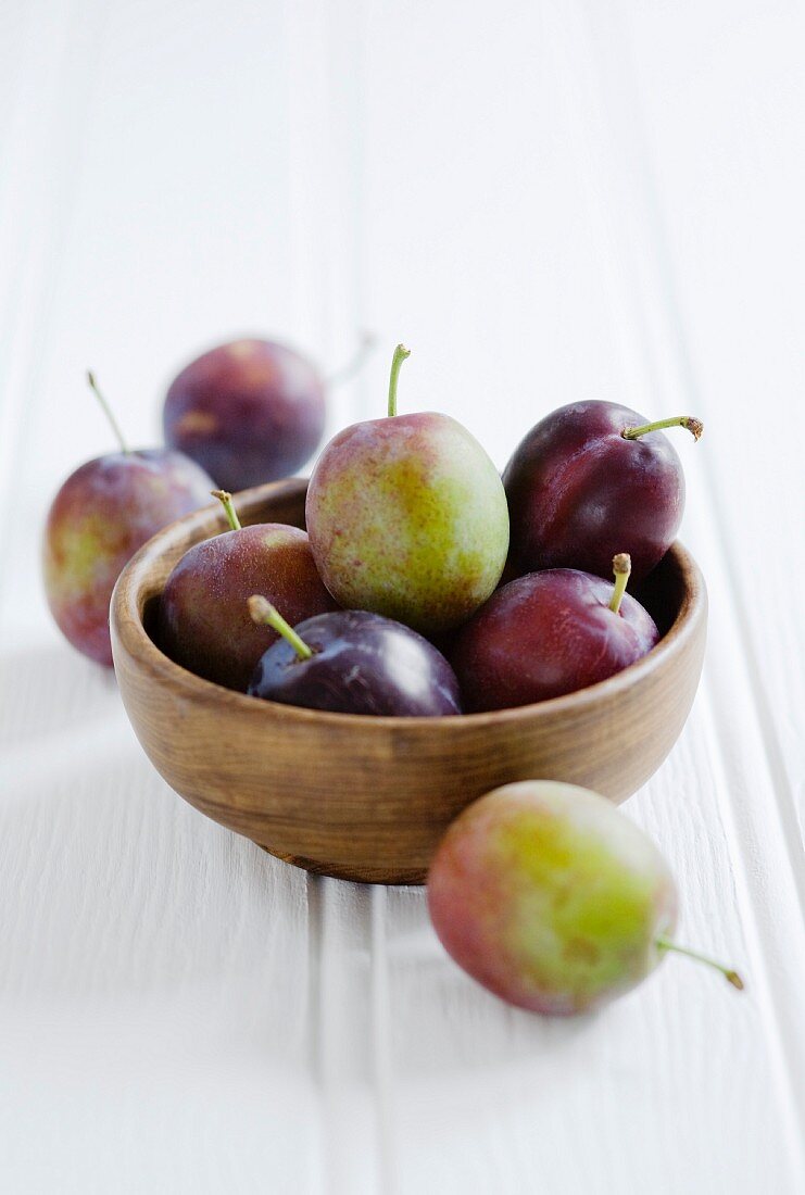 Fresh plums on a wooden bowl