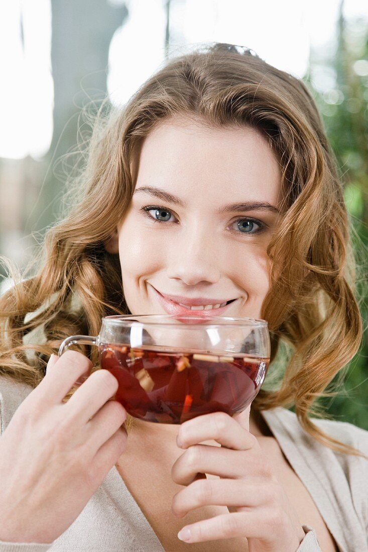 A young woman drinking a cup of fruit tea