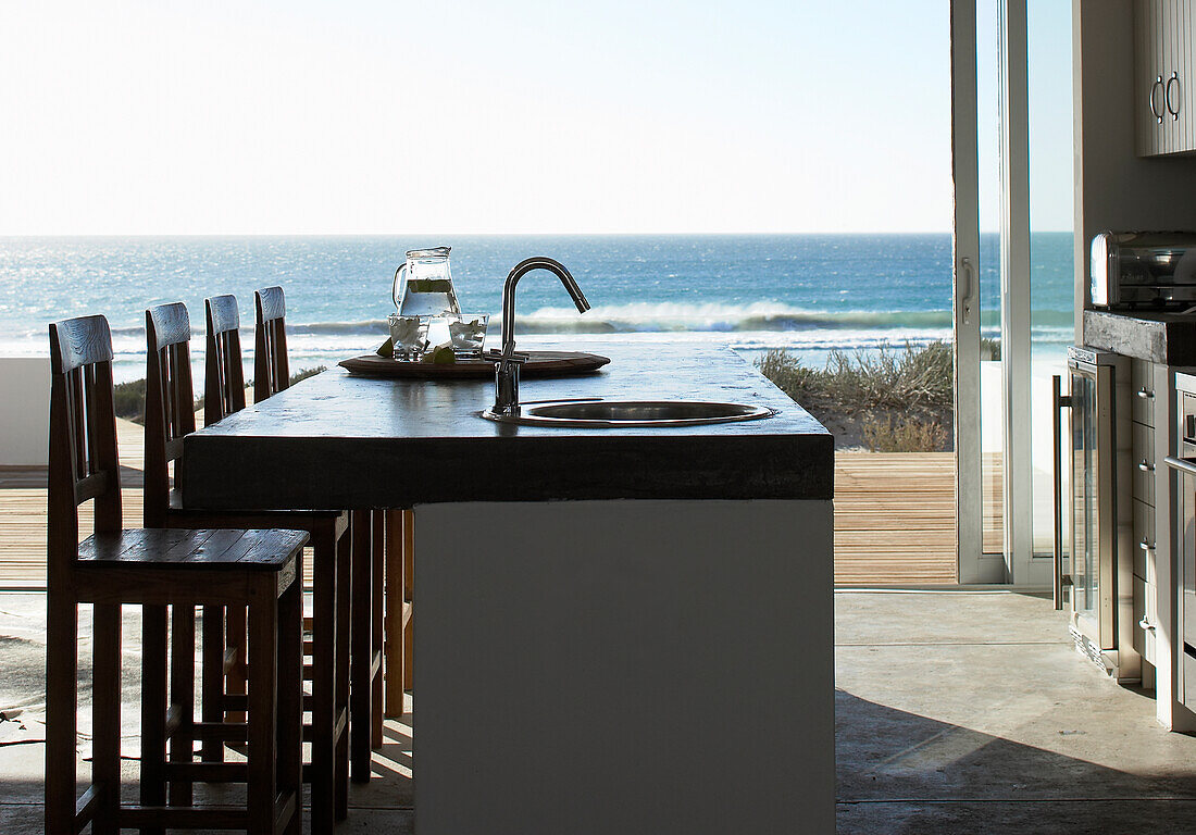 Kitchen island with sea view and bar stools on terrace