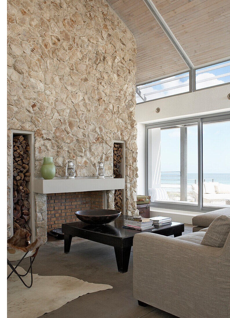 Living room with natural stone wall and sea view through large windows