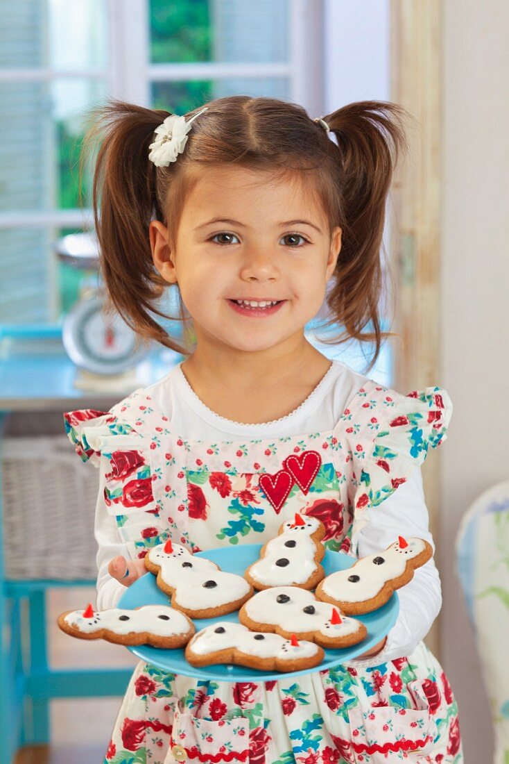 Mädchen hält Teller mit Lebkuchen-Schneemännern