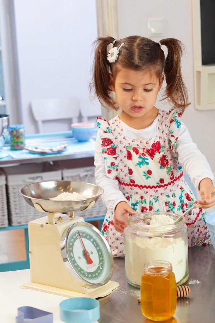 A little girl weighing ingredients in a kitchen