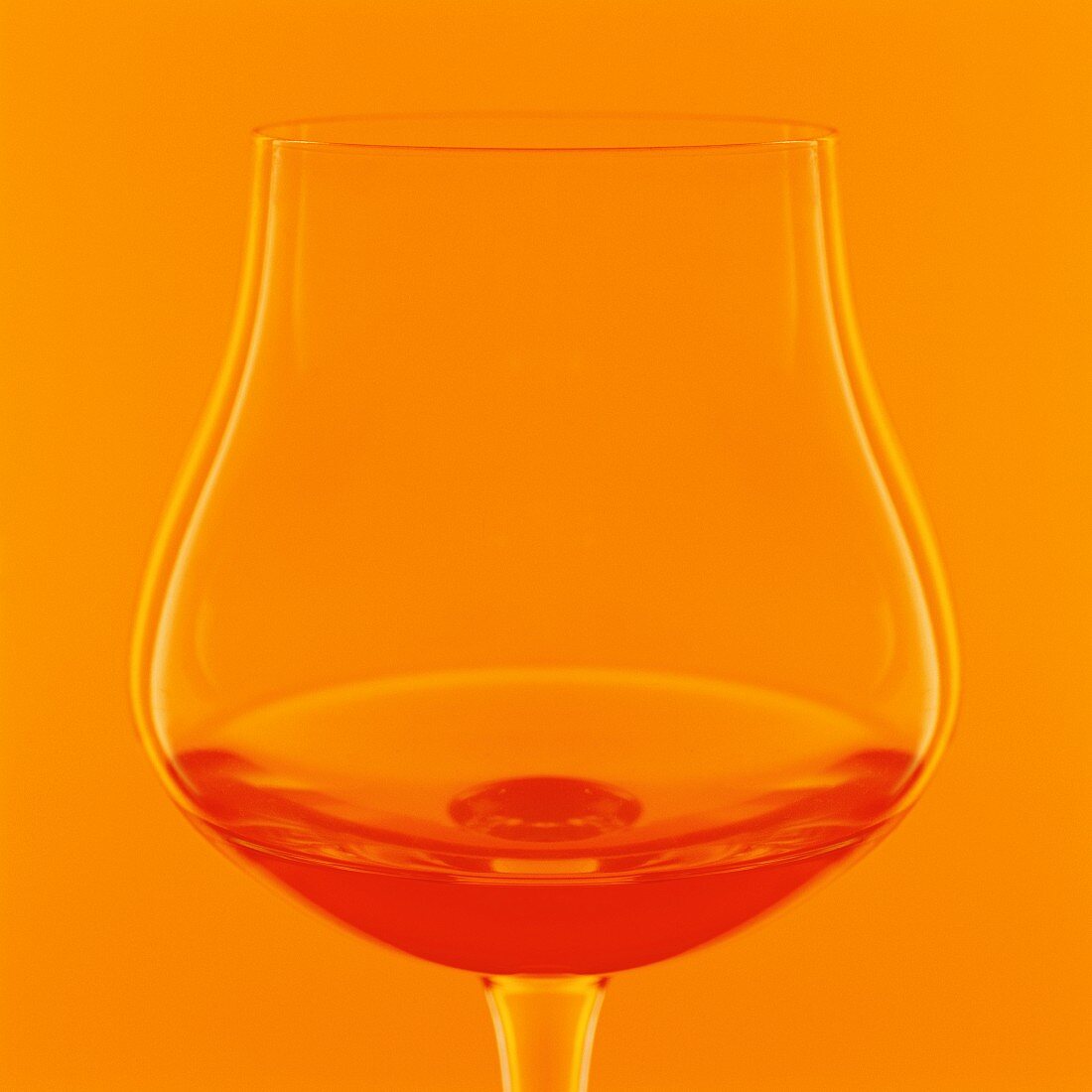 Ein Glas Cognac vor orangefarbenem Hintergrund