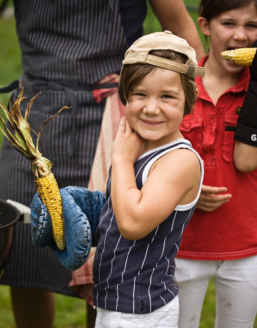 Children with grilled corn cobs