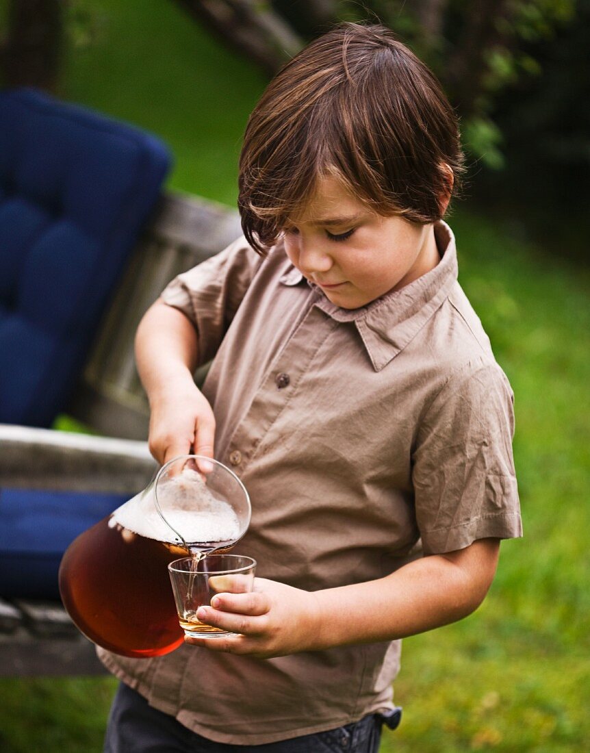 A boy pouring juice into a glass