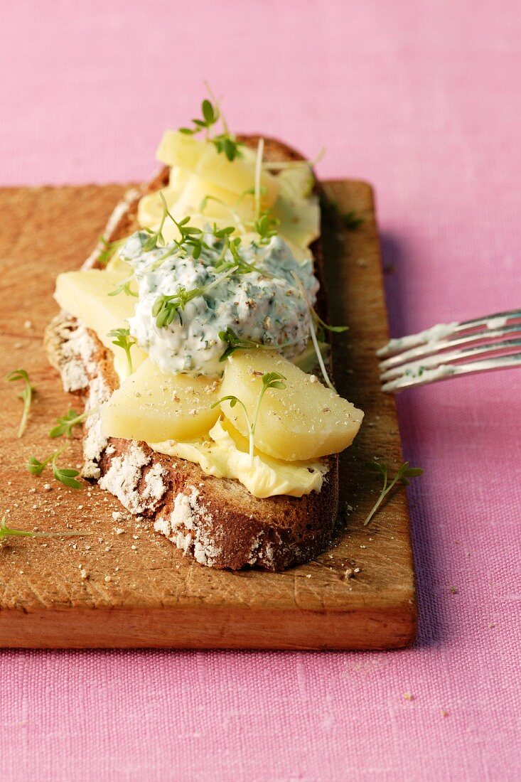 A slice of bread topped with sliced potatoes and herb quark