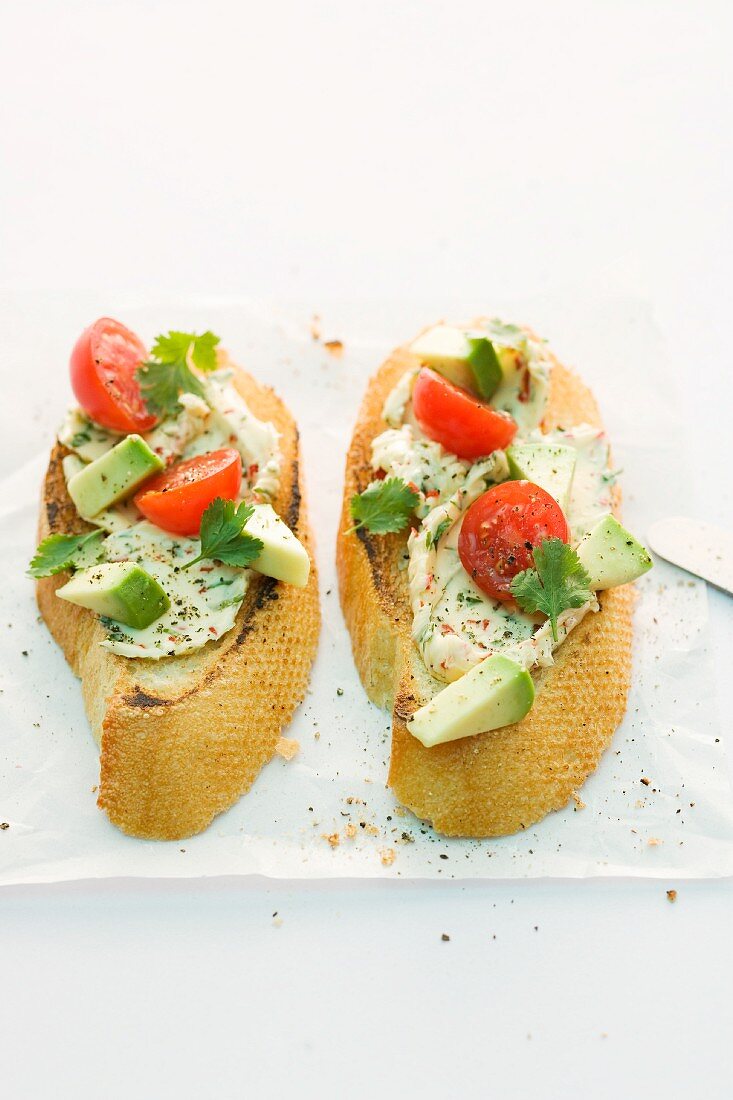Toasted baguette slices with chilli butter, tomatoes and avocado