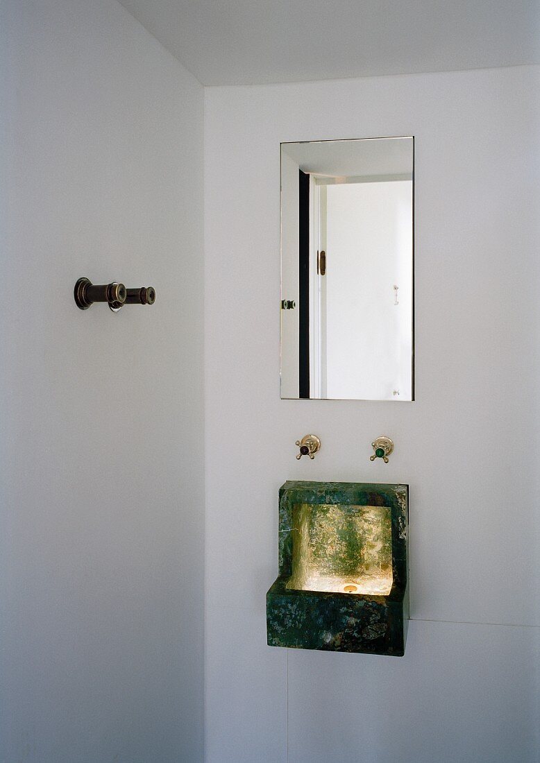 Small sink hung on wall beneath mirror