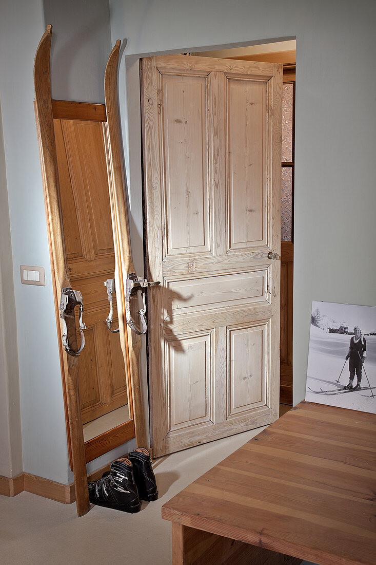 Hand-made, full-length mirror constructed from vintage skis and ski boots next to open door