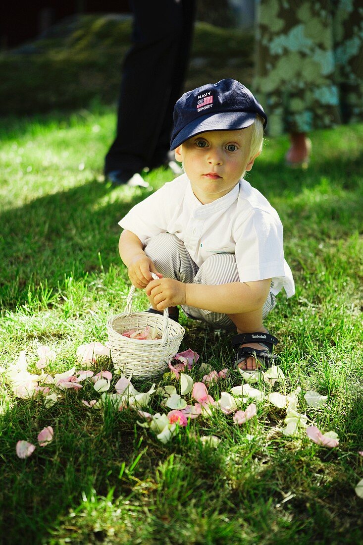 Little boy with basket and rose petals in garden