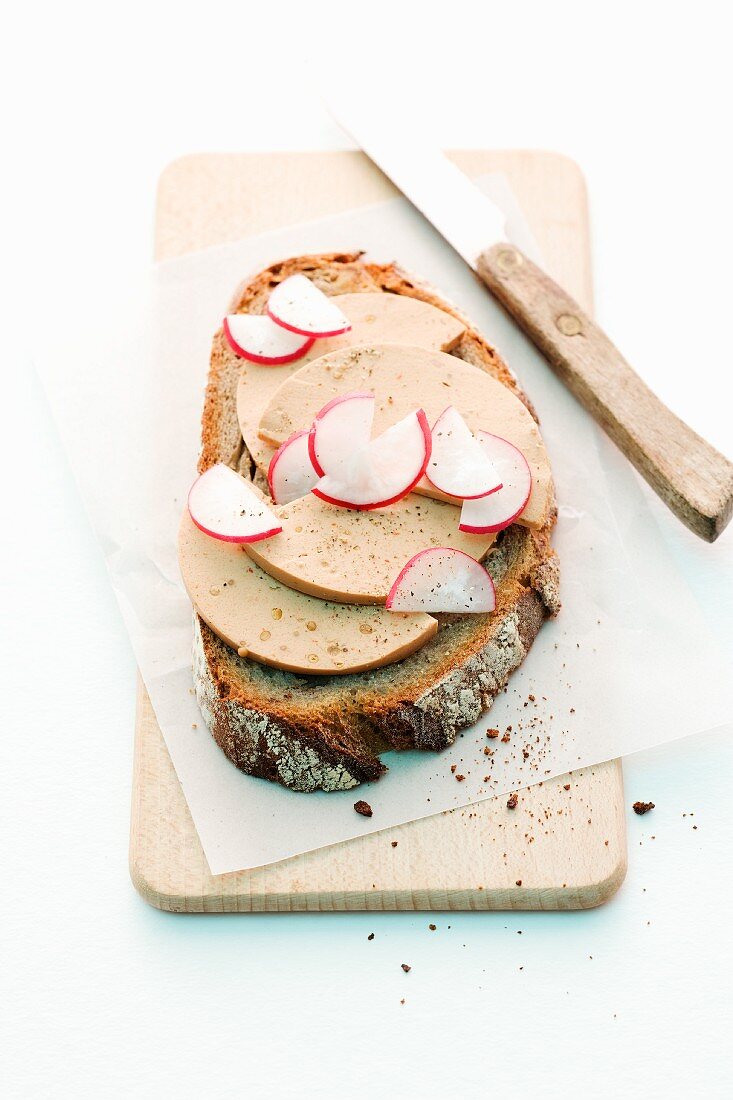 A slice of bread topped with pepper Bologna sausage and radishes