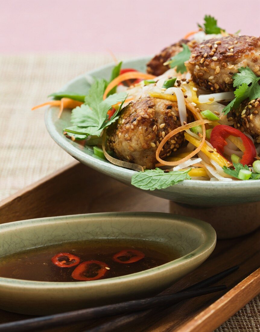 Chicken fritters with sesame seeds on vegetables (Asia)