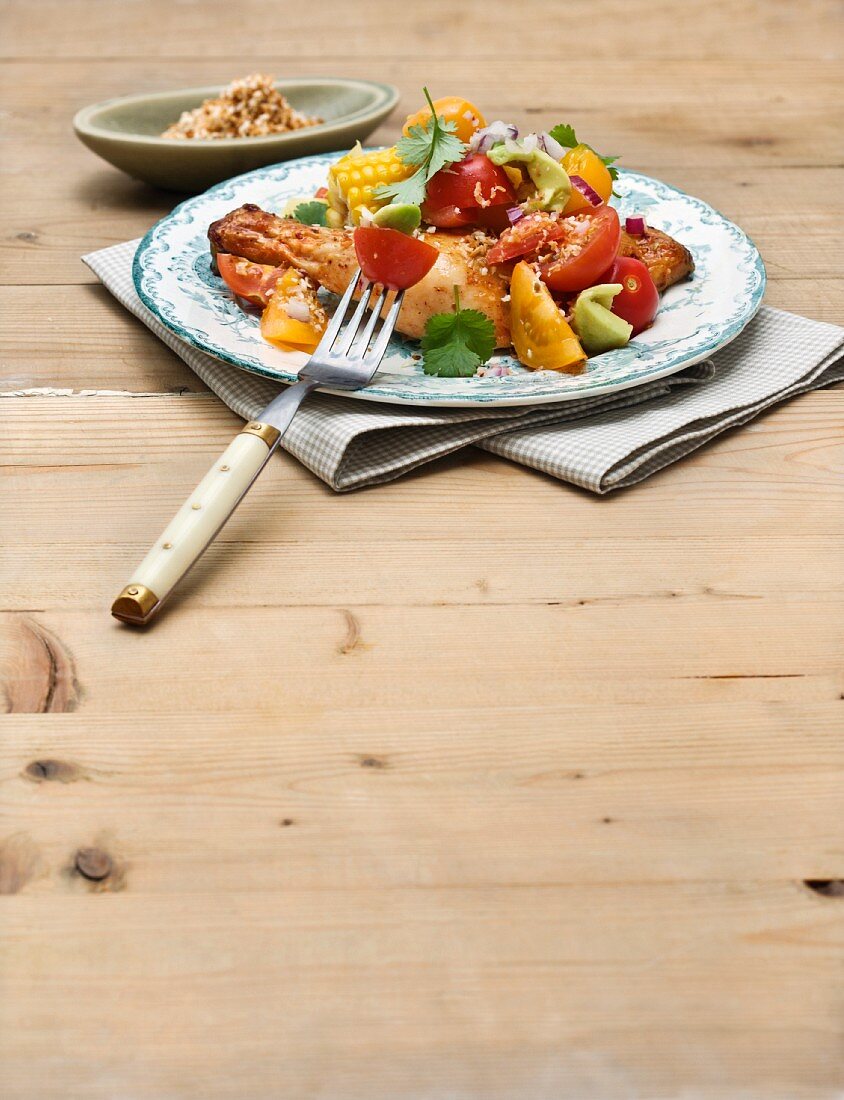 Chicken legs with corn cobs and tomato salad