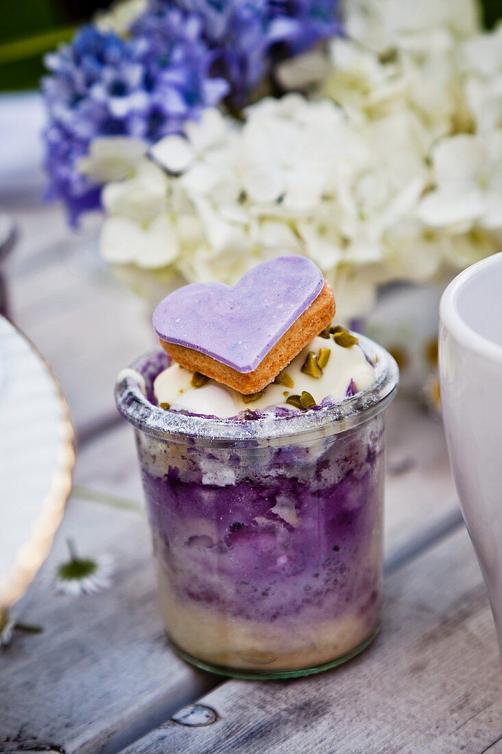 A mini cheese cake with blueberries and a purple heart biscuit