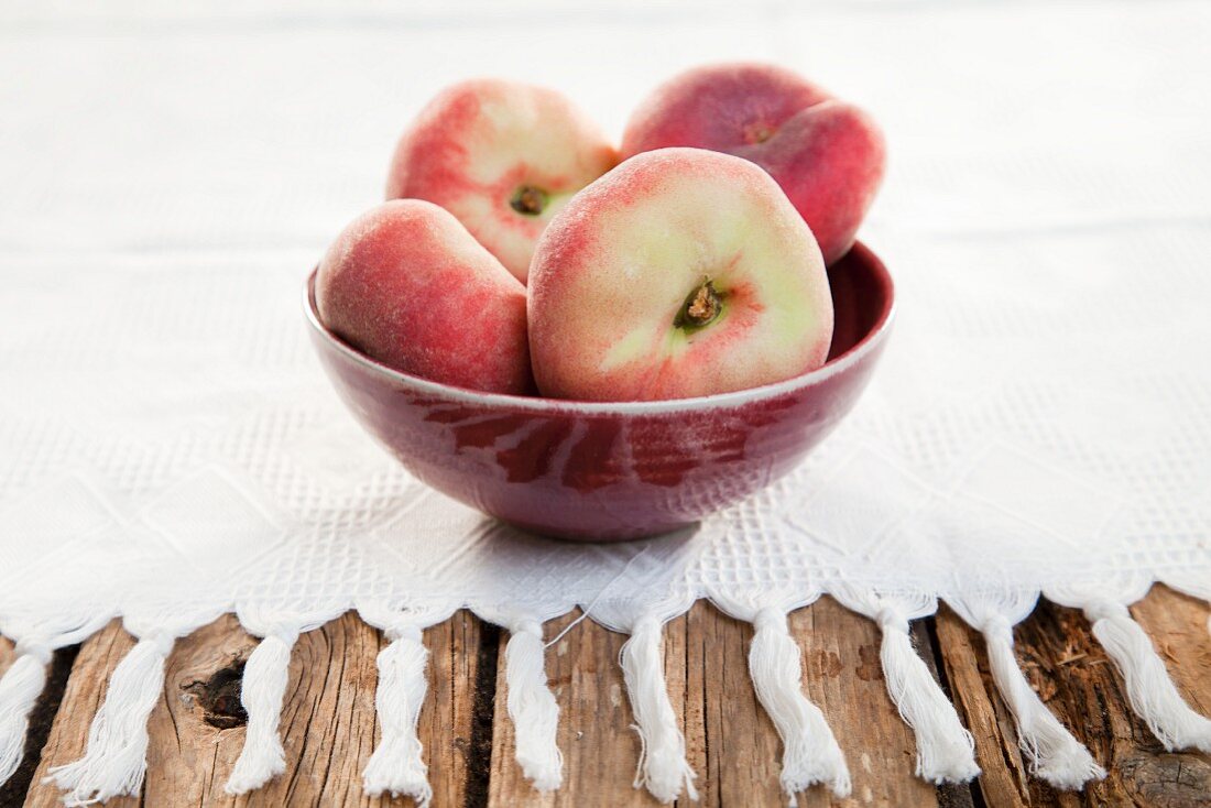 Vineyard peaches in a bowl on a white cloth