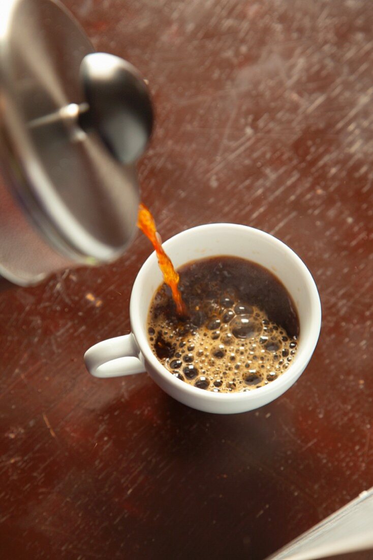 Hot Coffee Pouring From a Red Coffee Pot into a Red Coffee Cup