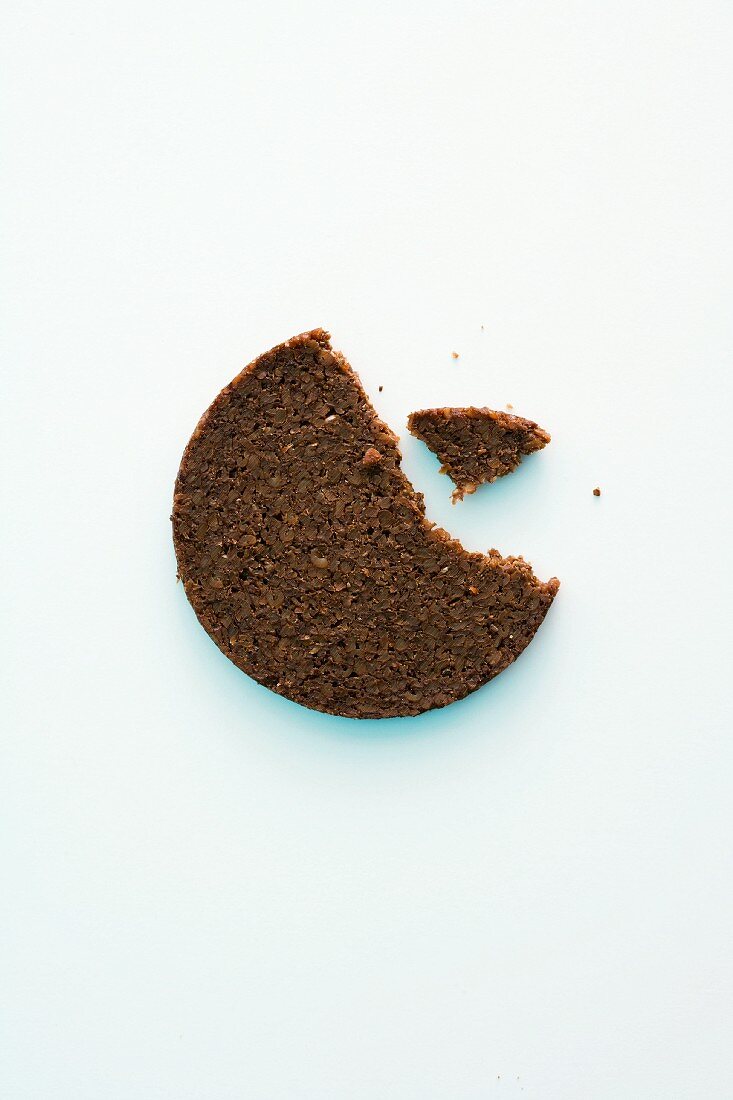 A slice of pumpernickel bread with a bite taken out