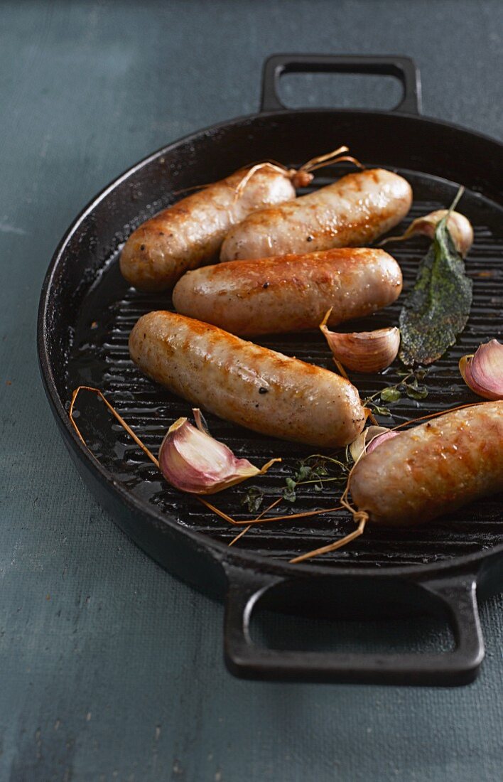 Bratwürstchen mit Knoblauch und Salbei in Grillpfanne