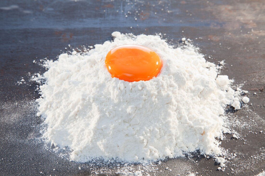 An egg yolk on a pile of flour
