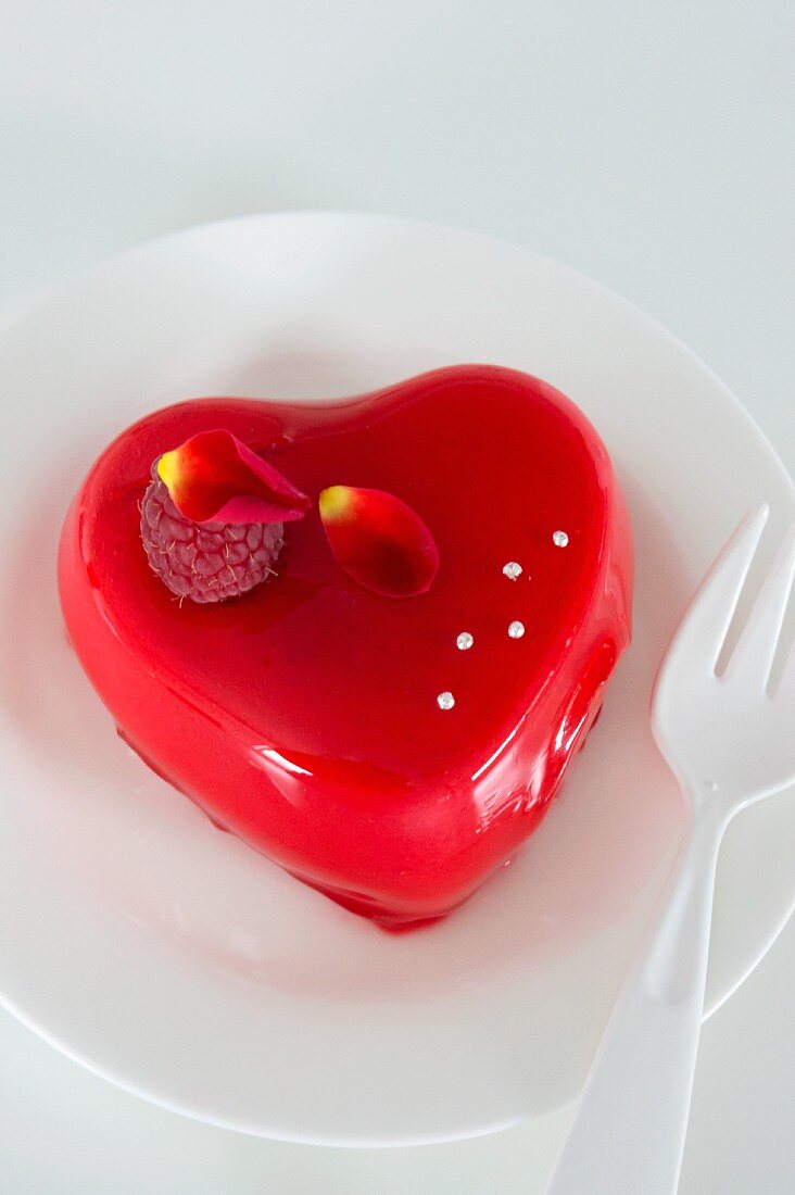 A heart-shaped rose pudding decorated with a raspberry