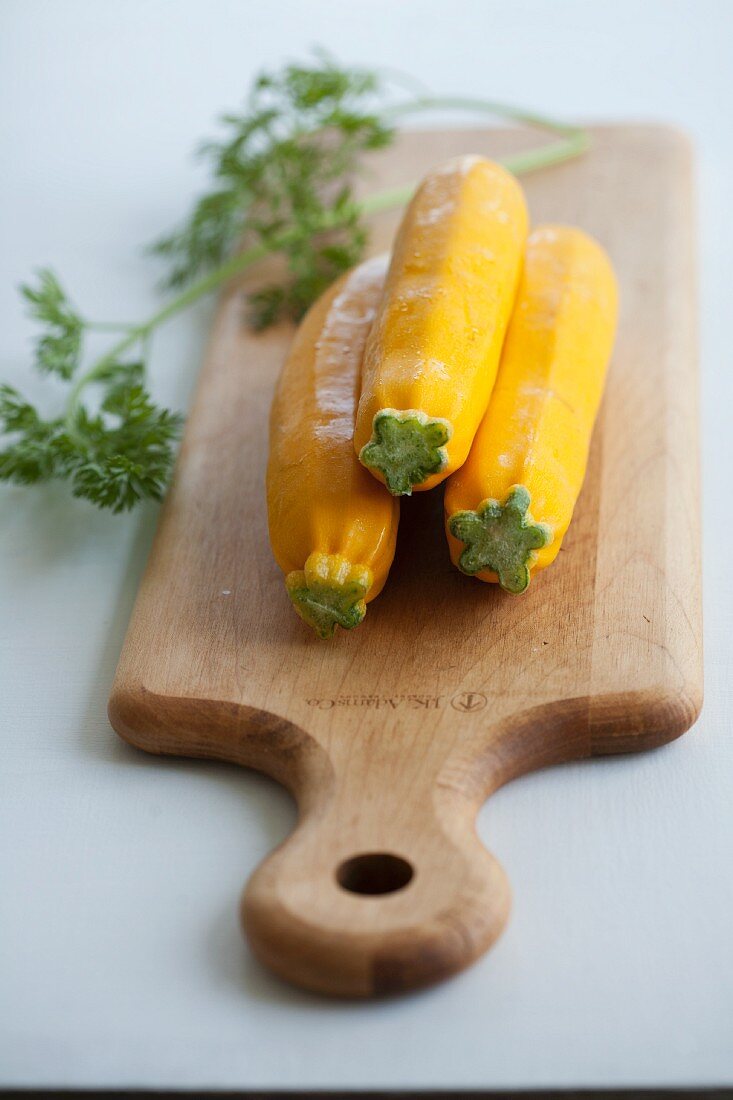 Three yellow courgettes on a chopping board