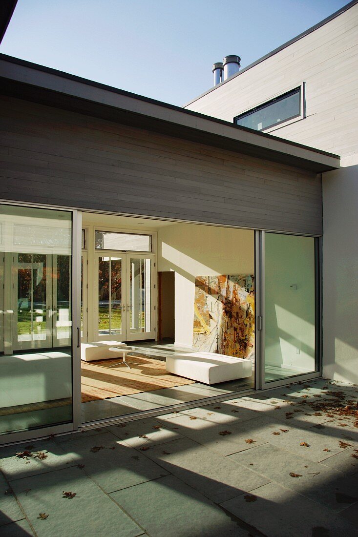 Autumnal courtyard and view of living space through open sliding glass door