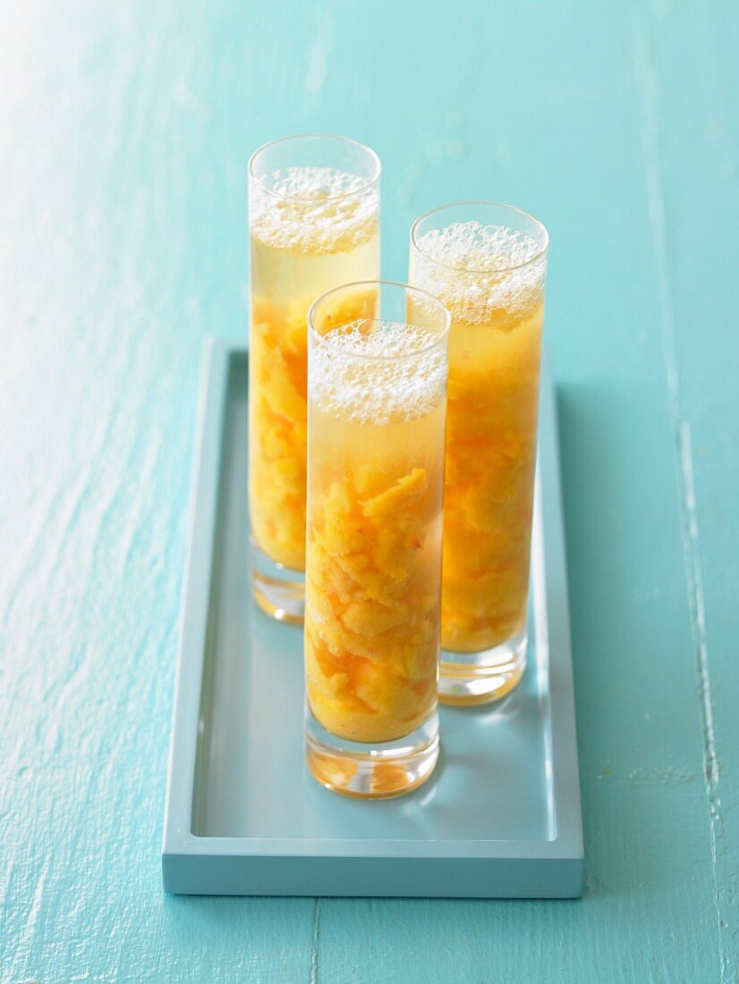 Three Mango Peach Drinks in Tall Glasses on Blue Tray