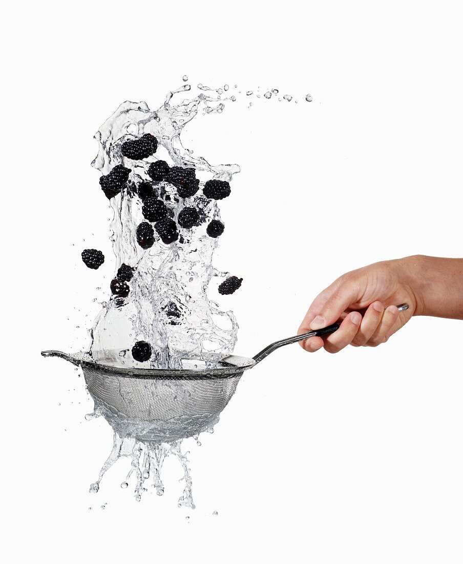 Blackberries being washed in a sieve