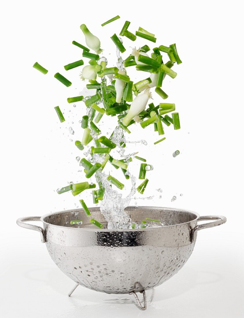 Spring onions and splash of water falling into a colander