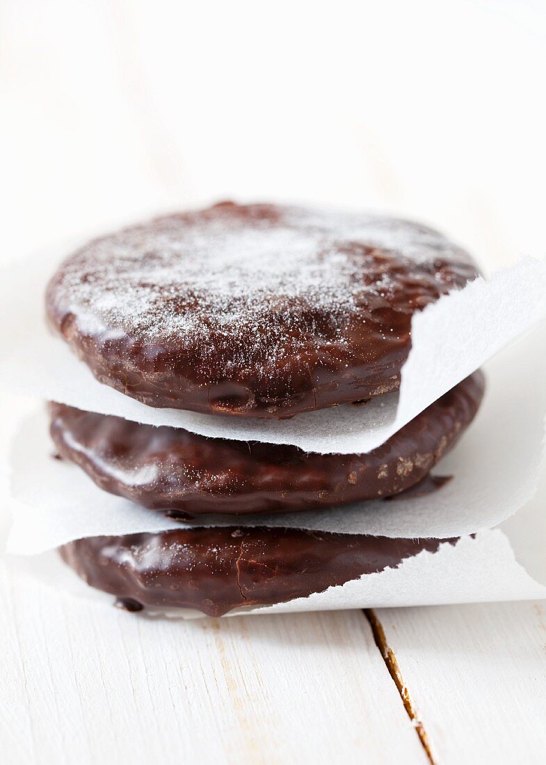 Three chocolate-covered wafers with icing sugar