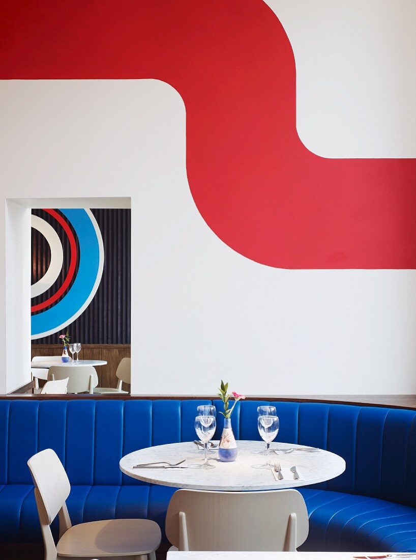 Table and chairs in front of blue upholstered bench