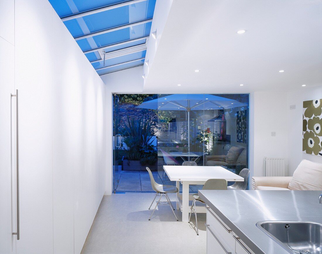 Moderner Wohnraum mit Blick durch Glasfront auf Terrasse in Abendstimmung