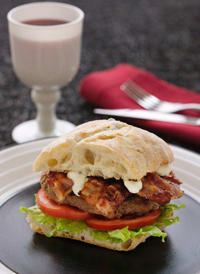 Hamburger with bacon, mayonnaise, tomato and lettuce