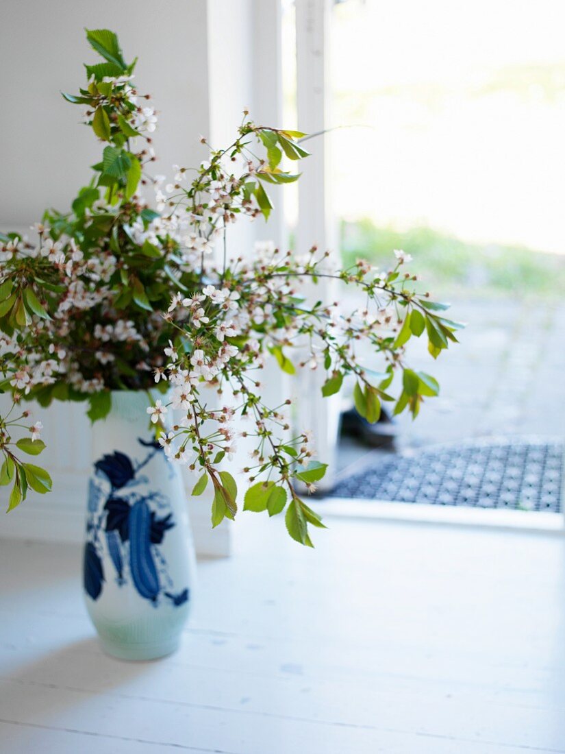 Vase of blossoming twigs on floor