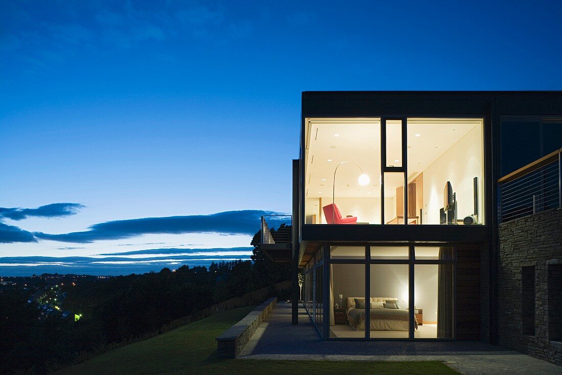 Illuminated house with glass walls at dusk