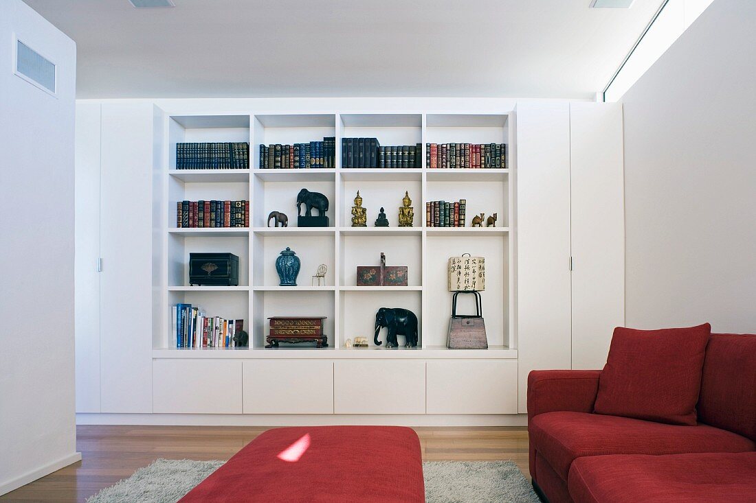 Wohnzimmer mit roter Sofagarnitur und eingebautem Bücherregal