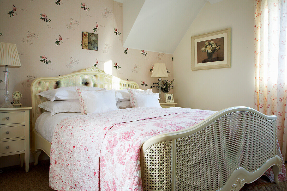 Schlafzimmer im Landhausstil mit floraler Bettwäsche und Rattanbett