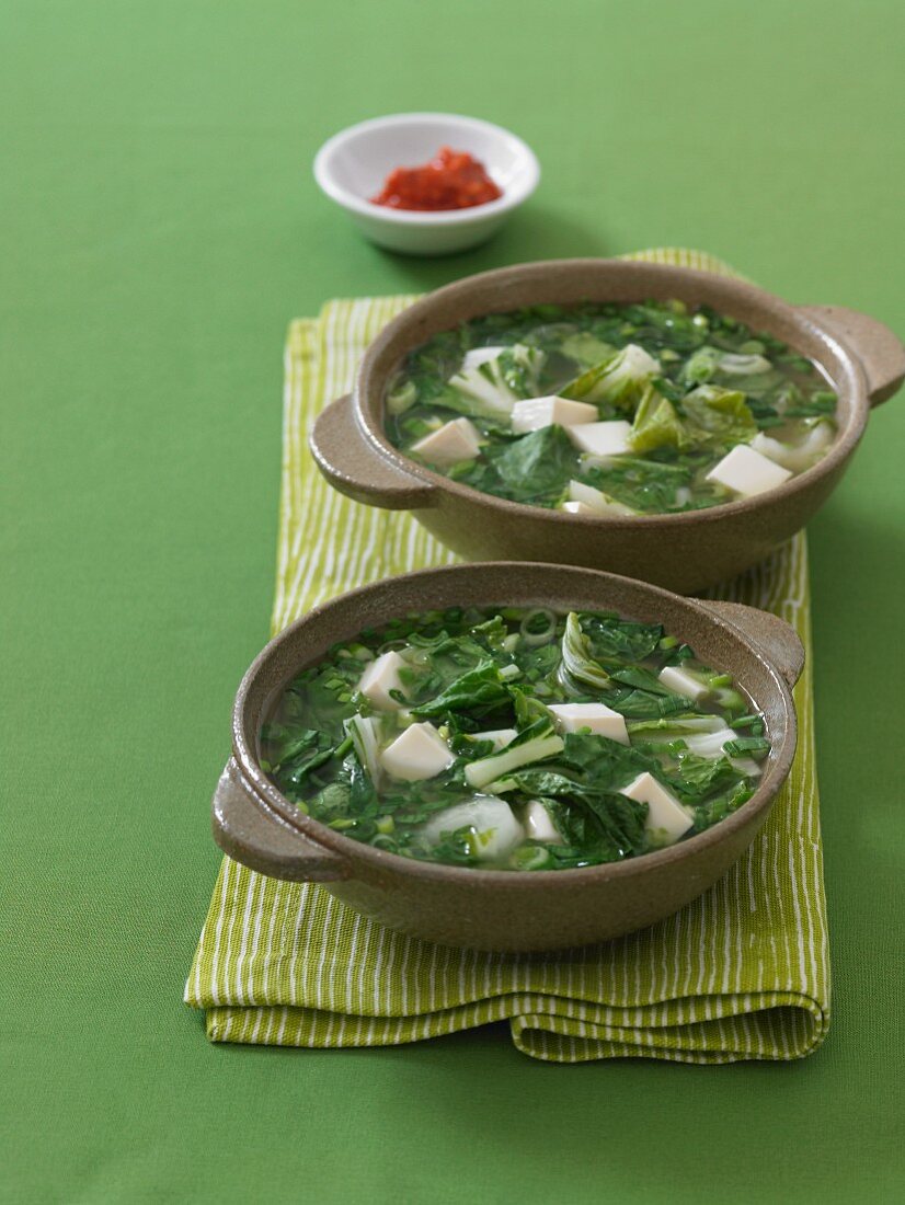 Two Bowls of Tofu and Greens Soup on a Green Napkin