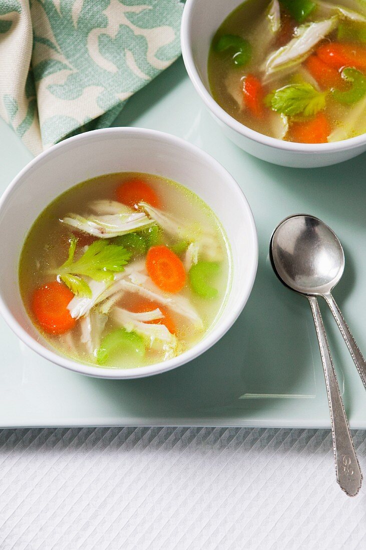 Two Bowls of Chicken Soup on a Tray with Two Spoons
