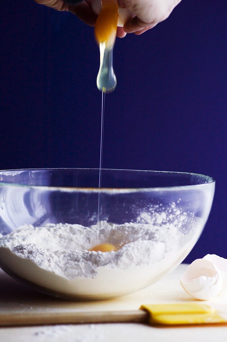 Hands Cracking an Egg into a Bowl of Flour