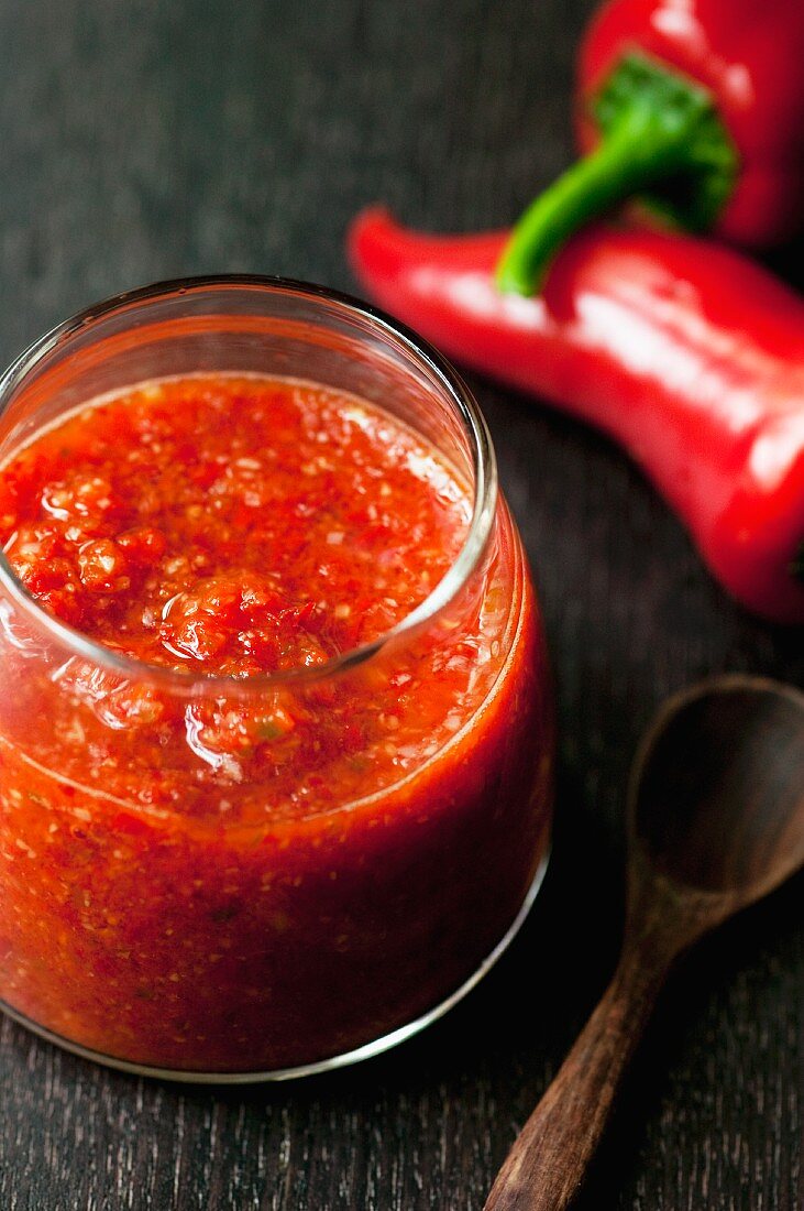 Chilisauce im Glas und frische rote Chilischoten