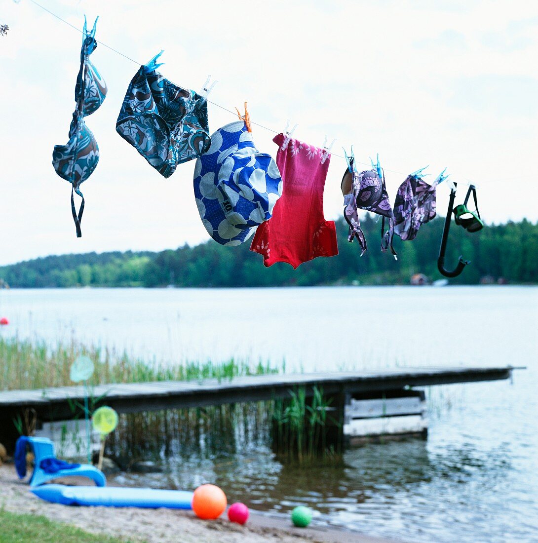 Badesachen hängen auf der Wäscheleine am Steg