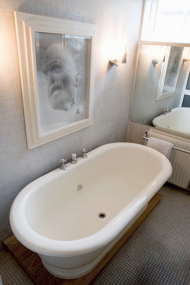 Bathroom with bathtub beneath portrait