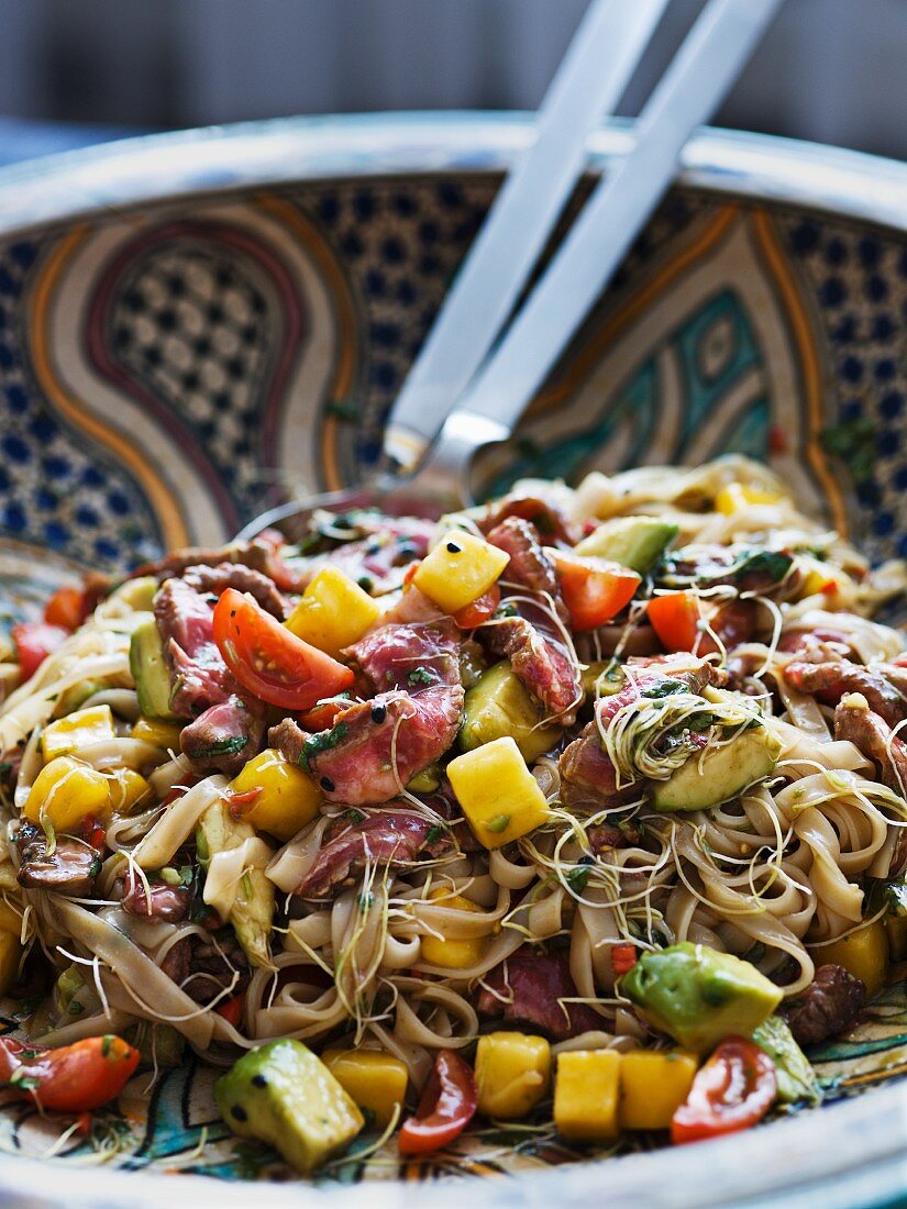 Pasta salad with beef, mango, avocado, bean sprouts and tomatoes (Asia)